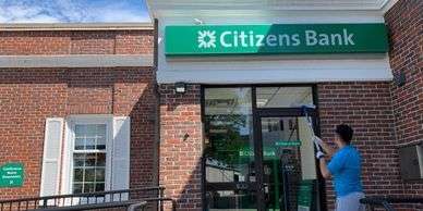 A man is cleaning the door of Citizen Bank